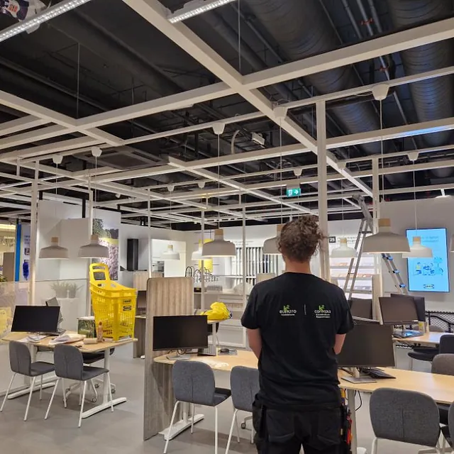 Elektriker installerer bærekraftig belysning på IKEA-lager, elektroinstallasjon og energieffektive løsninger.