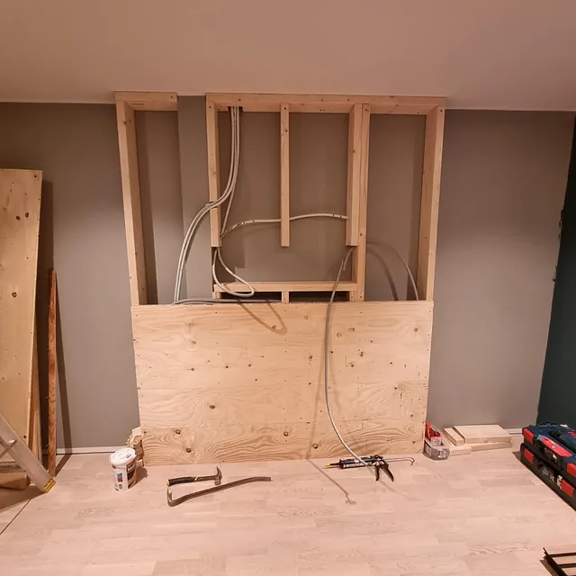 Elektriker jobber med renovering av en uferdig vegg, installerer elektriske anlegg for ferdigstillelse